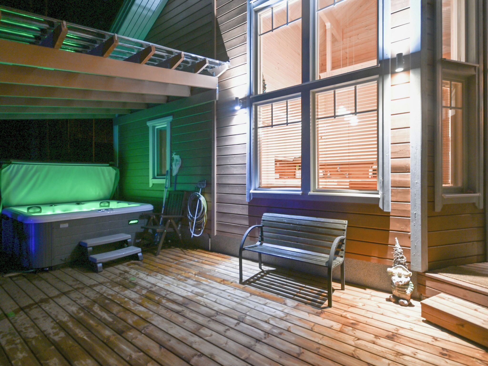 A cozy outdoor deck with a hot tub, a bench, and a small statue.