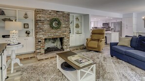 A living room with a brick fireplace, white cabinets, a blue sofa, and a brown armchair.