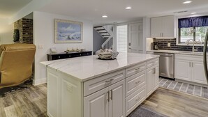 A modern kitchen with white cabinetry, a marble countertop, and stainless steel appliances.