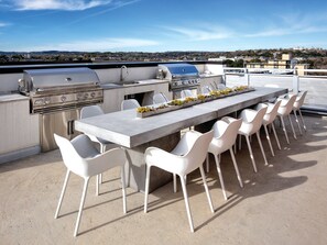 An outdoor kitchen with a grill, seating, and a view of the city. - DOWNTOWN Austin with ROOFTOP Pool and BBQ Area, Fire Pit & a Fitness Center (Austin)