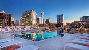 A rooftop pool with lounge chairs and a city skyline view. - DOWNTOWN Austin with ROOFTOP Pool and BBQ Area, Fire Pit & a Fitness Center (Austin)