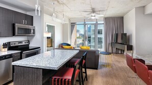 A modern kitchen with a granite countertop, stainless steel appliances, and a dining area with a bar stool and red chairs. - DOWNTOWN Austin with ROOFTOP Pool and BBQ Area, Fire Pit & a Fitness Center (Austin)