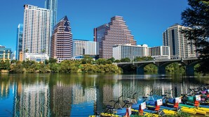 A cityscape with modern high-rise buildings, a river, and a bridge. - DOWNTOWN Austin with ROOFTOP Pool and BBQ Area, Fire Pit & a Fitness Center (Austin)