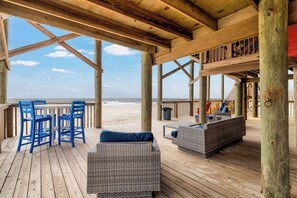 A wooden deck with wicker furniture, a table, and chairs overlooking the beach. - Livin the Dream - Beachfront, 6/6, POOL, Pet Friendly, Sleeps 15 (Dauphin Island)