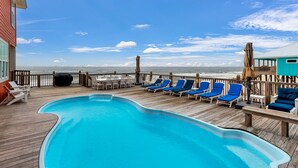 A pool area with blue lounge chairs and a view of the ocean. - Livin the Dream - Beachfront, 6/6, POOL, Pet Friendly, Sleeps 15 (Dauphin Island)