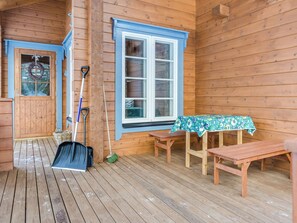 A wooden cabin with a porch, a table with a floral tablecloth, and various cleaning tools. - Pihlajapelto by Interhome (Juuka)