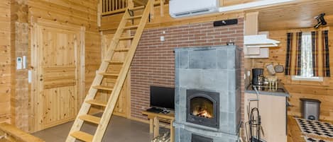 Ein Holzblock-Interieur mit Kamin, Fernseher und einer Holztreppe.