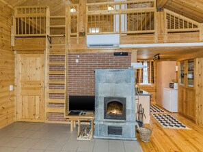 A wooden interior with a fireplace, a television, and a kitchen area.