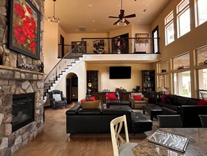 A spacious living area with a fireplace, a staircase to an upper level, and a large window providing natural light.
