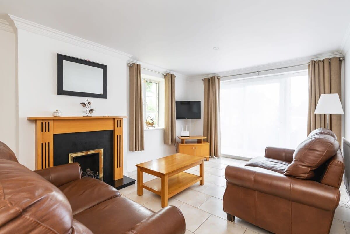 A living room with a fireplace, leather sofas, a wooden coffee table, and a television.