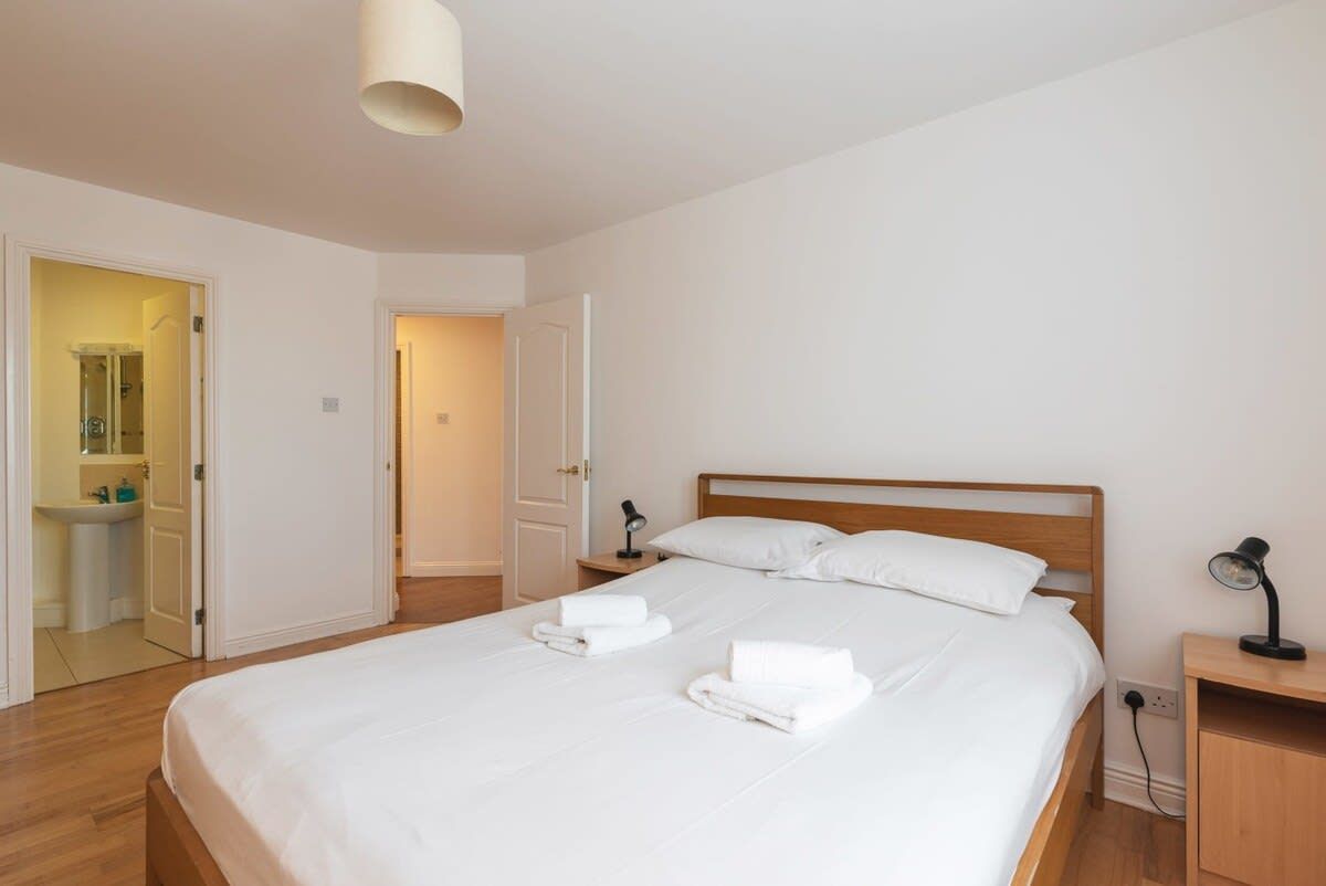 A bedroom with a bed, a nightstand, and a lamp.