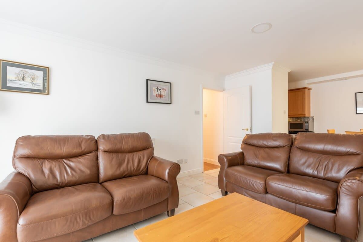 Una sala de estar con dos sofás de cuero marrón y una mesa de centro de madera.