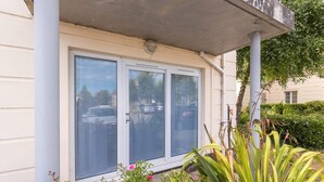 A building with a white exterior, a covered porch, and a window with a view of parked cars and greenery. - Ferncourt Stepaside S (Dublin)
