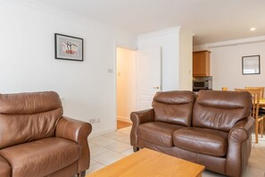 A living room with two brown leather sofas, a wooden coffee table, and a framed picture on the wall. - Ferncourt Stepaside S (Dublin)