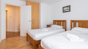 A room with two wooden beds, white bedding, a wooden wardrobe, and a framed picture on the wall. - Ferncourt Stepaside S (Dublin)