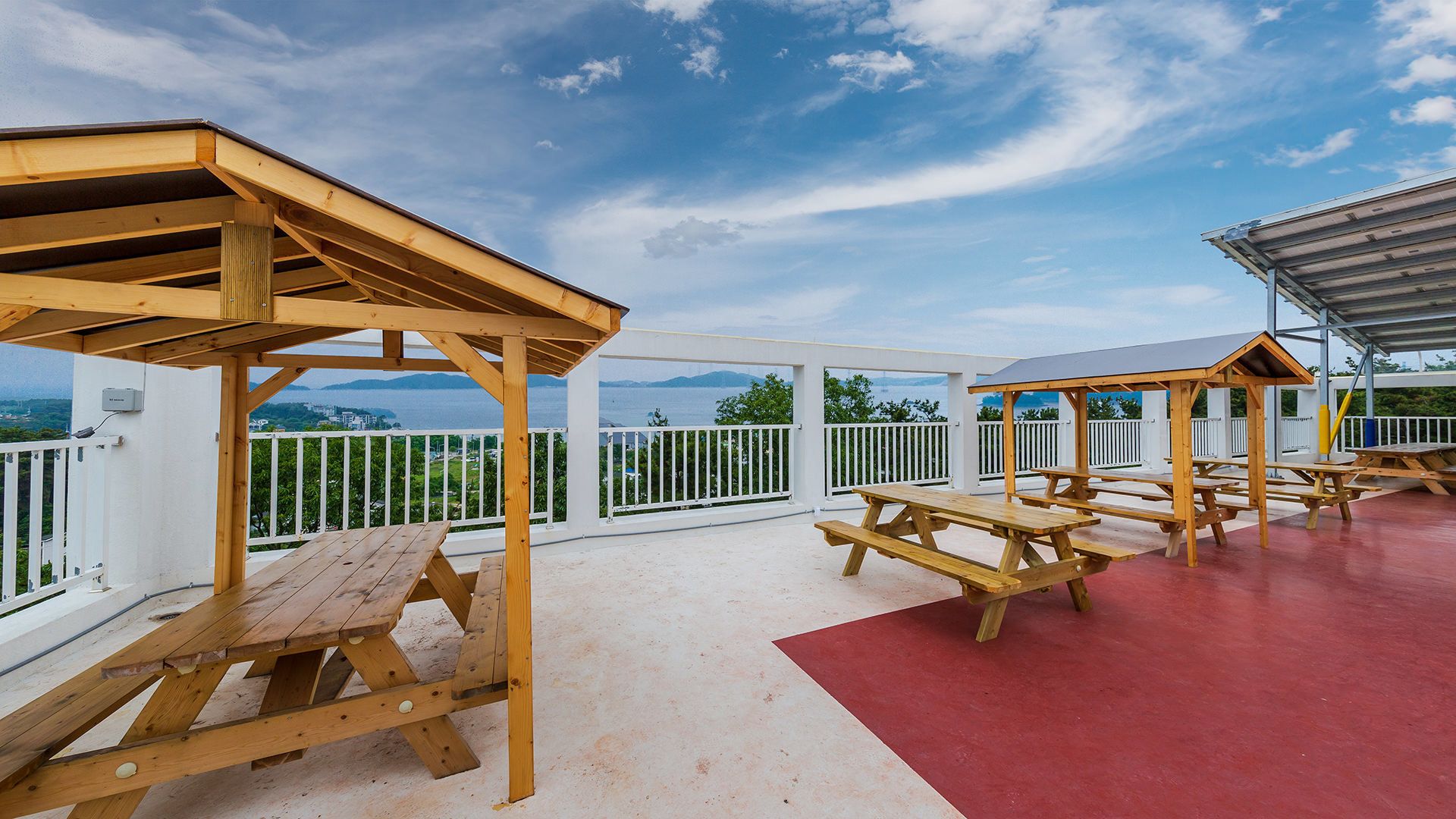 A covered outdoor area with picnic tables and a view of the sea.