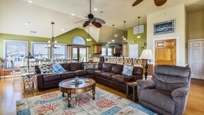 A spacious living room with a sectional sofa, a round coffee table, and a high ceiling with a ceiling fan. - Coastal Castle: Pool, Dog-friendly, Separate Guest House, 530 Ft to Beach (Corolla)
