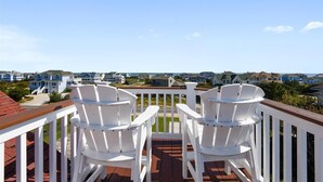 A balcony with two white Adirondack chairs overlooking a residential area with houses and a clear sky. - Coastal Castle: Pool, Dog-friendly, Separate Guest House, 530 Ft to Beach (Corolla)