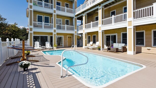 A two-story building with a pool area, including a pool, lounge chairs, and a deck. - Coastal Castle: Pool, Dog-friendly, Separate Guest House, 530 Ft to Beach (Corolla)