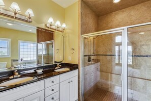 Une salle de bain avec deux vasques, un meuble-lavabo et une douche à parois de verre.