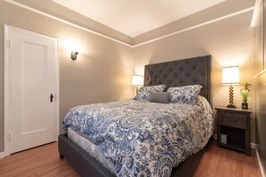 Un dormitorio con una cama grande, una mesita de noche con una lámpara y una puerta.