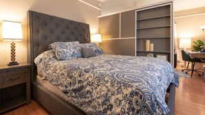 Ein Schlafzimmer mit einem großen Bett, einem Nachttisch, einem Schreibtisch und einem eingebauten Bücherregal.