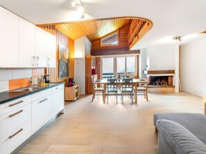 Eine moderne Küche mit weißen Schränken, einer Holzbalkendecke und einem Essbereich mit Kamin.
