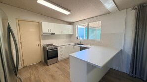 A compact kitchen with white cabinets, a stainless steel stove, and a window with a view of a swimming pool.