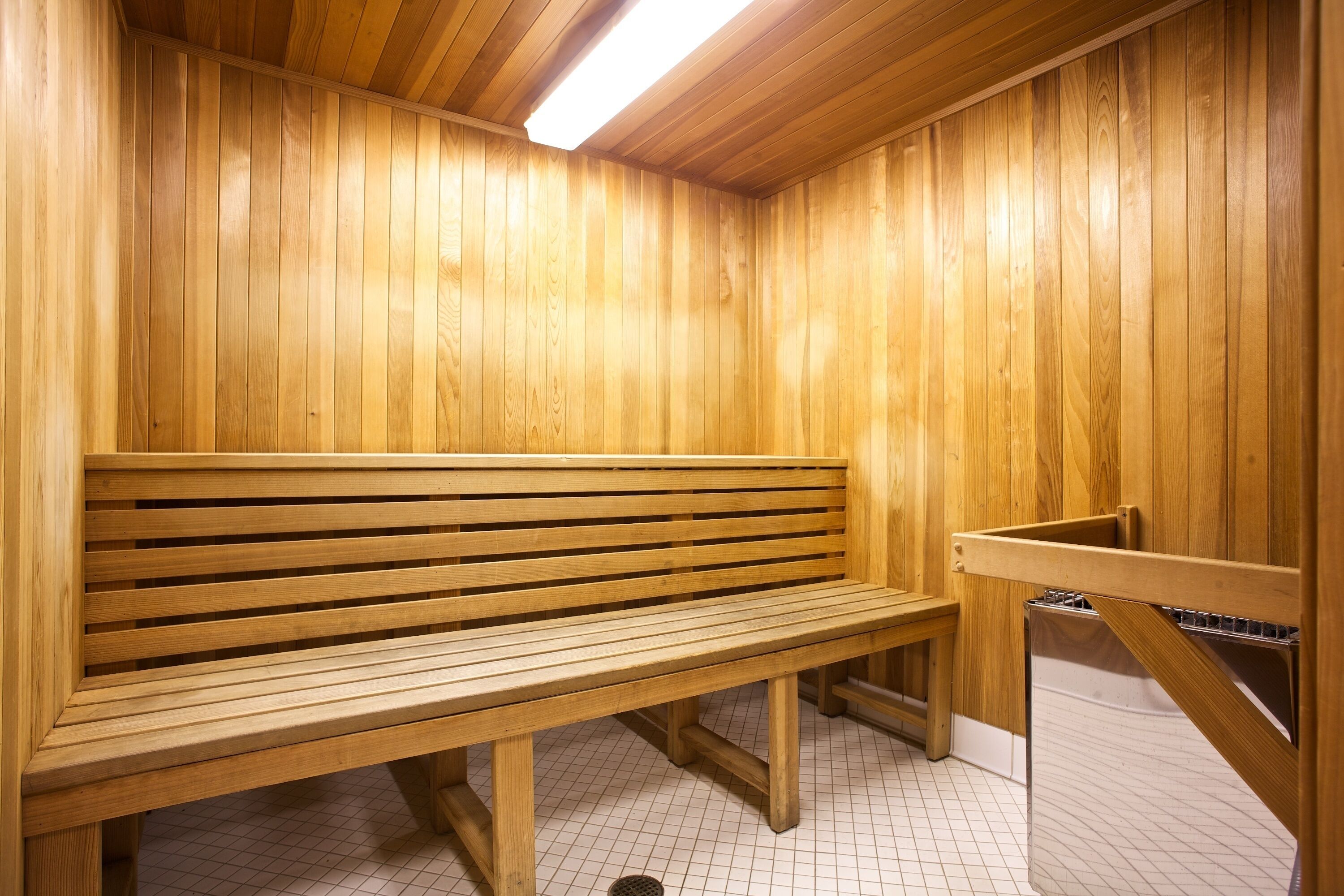 A wooden sauna with a bench and a metal bench.