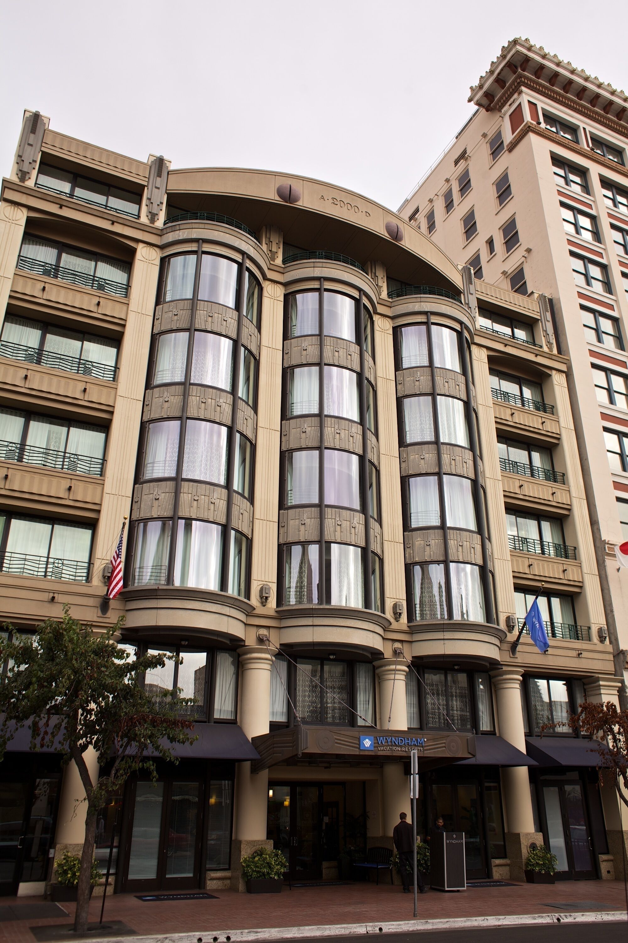 A hotel with a curved facade, multiple balconies, and a prominent entrance with a blue awning.