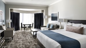 Une chambre d’hôtel avec un grand lit, un bureau, une chaise, un canapé et une table à manger.