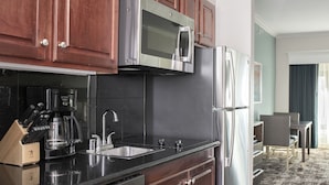 Une cuisine moderne avec des meubles en bois, des appareils en acier inoxydable et un plan de travail noir.