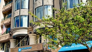 Un hôtel doté d’une façade moderne, de grandes fenêtres et d’une entrée bien visible, surmontée d’un auvent bleu.