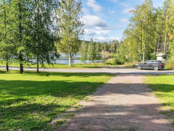 A gravel path leading to a lake with a car parked nearby.