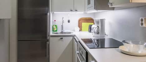 A modern kitchen with a stainless steel refrigerator, a built-in oven, a coffee maker, and a toaster.