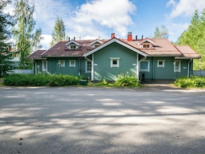 A two-story house with a red-tiled roof, green siding, and a front driveway.