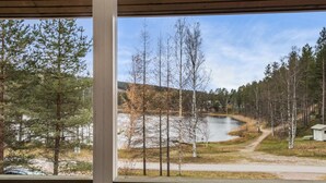 A view through a window of a cabin with a lake, trees, and a path. - Mustikka by Interhome (Sotkamo)