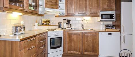 Una cocina con armarios de madera, un microondas, un horno y un lavamanos.