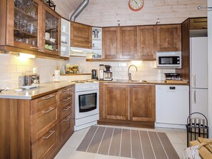 Eine Küche mit Holzausstattung, einer Mikrowelle, einem Backofen und einem Spülbecken.