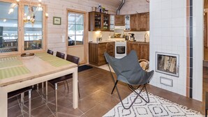 Una cocina acogedora con armarios de madera, una zona de comedor con mesa y sillas, y una chimenea.