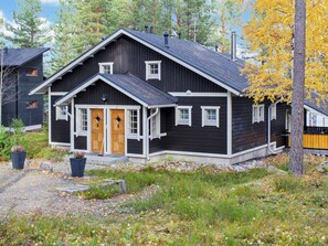 A two-story wooden house with a dark exterior, a front porch, and a chimney.