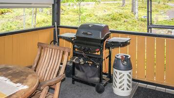 Eine Holzterrasse mit Grill, Stuhl und Laterne.