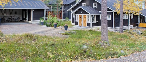 A row of cabins with a gravel driveway and surrounding trees.