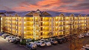 Un hotel de varios pisos con una escalera central, varios balcones y un estacionamiento.
