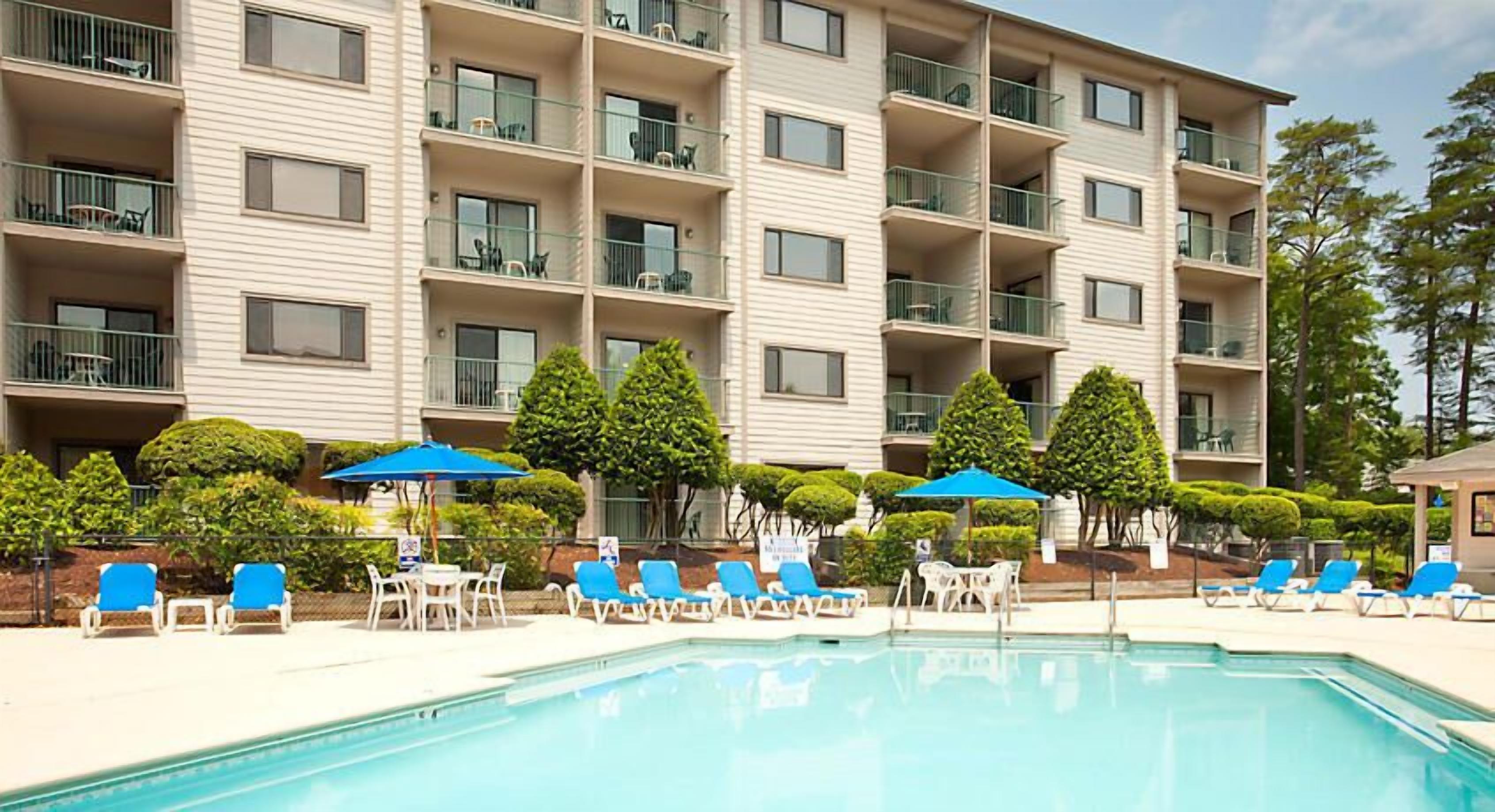 Ein Hotel mit Schwimmbad, mehreren Balkonen und Liegestühlen.