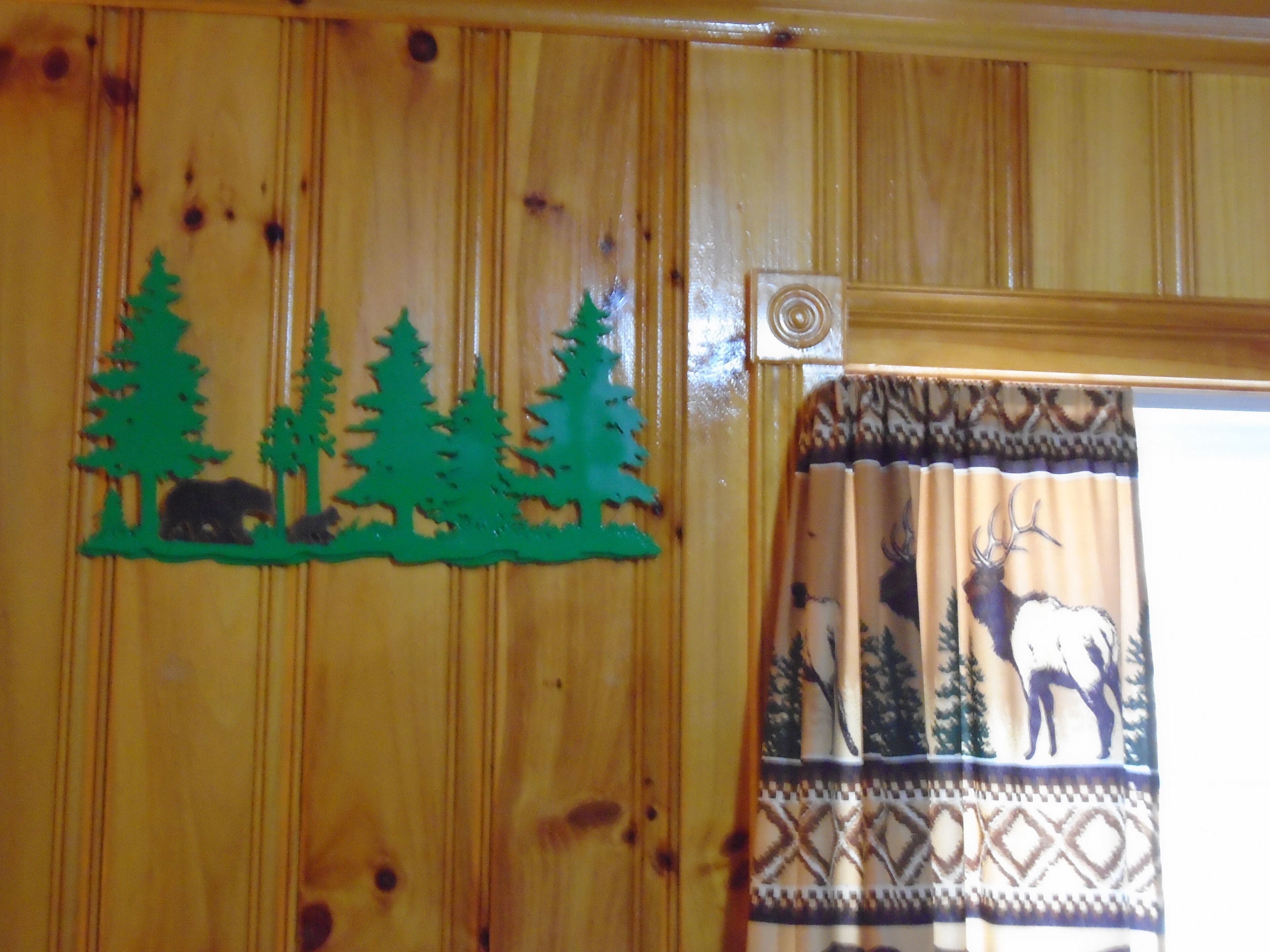 Un panel de madera con un corte decorativo de escena forestal y un cortinaje con diseño de ciervo.