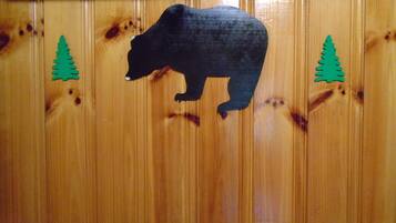 A wooden wall with a bear silhouette and two green tree cutouts.