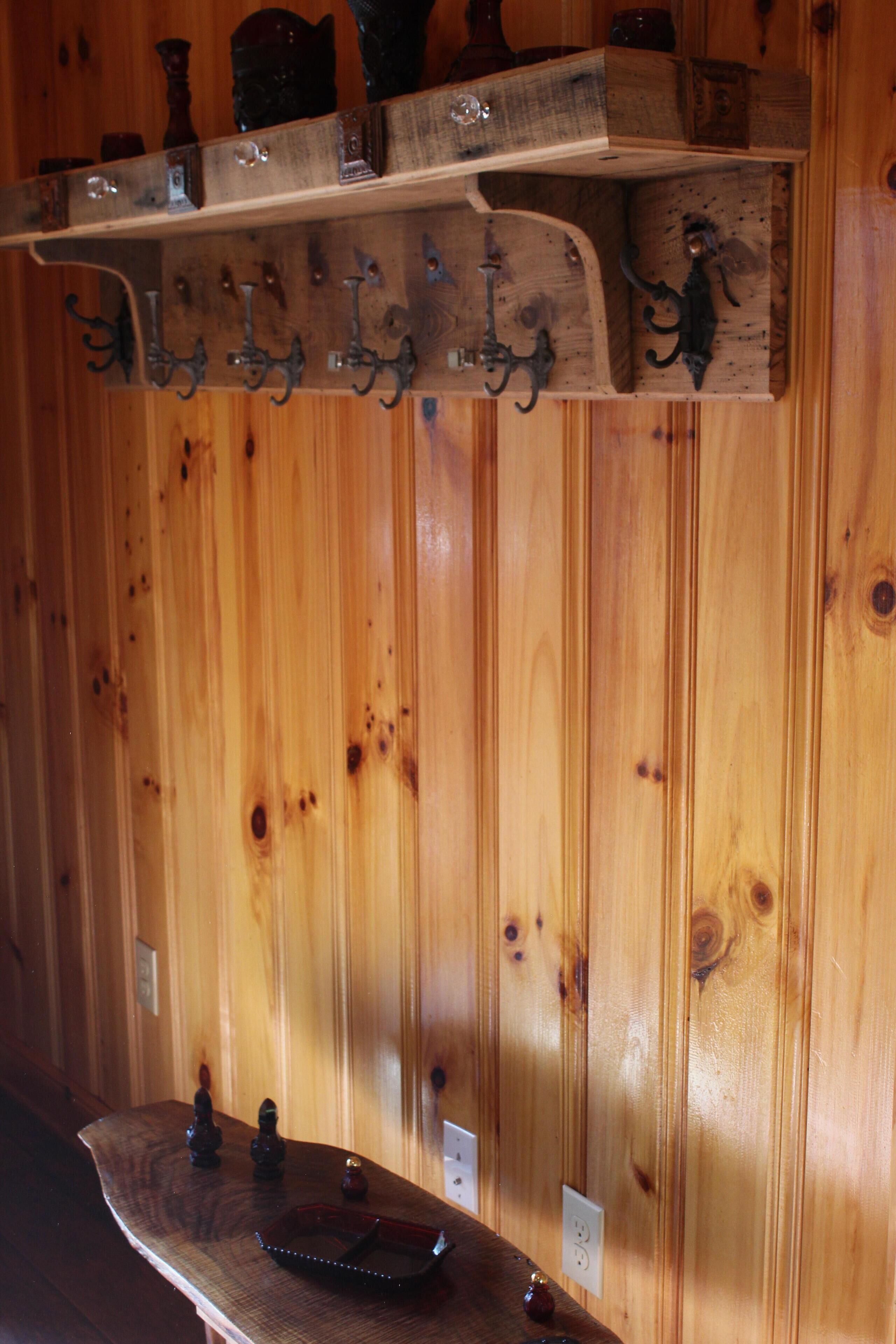 Una pared de madera con un estante que sostiene diversos objetos, incluyendo una bandeja con adornos.