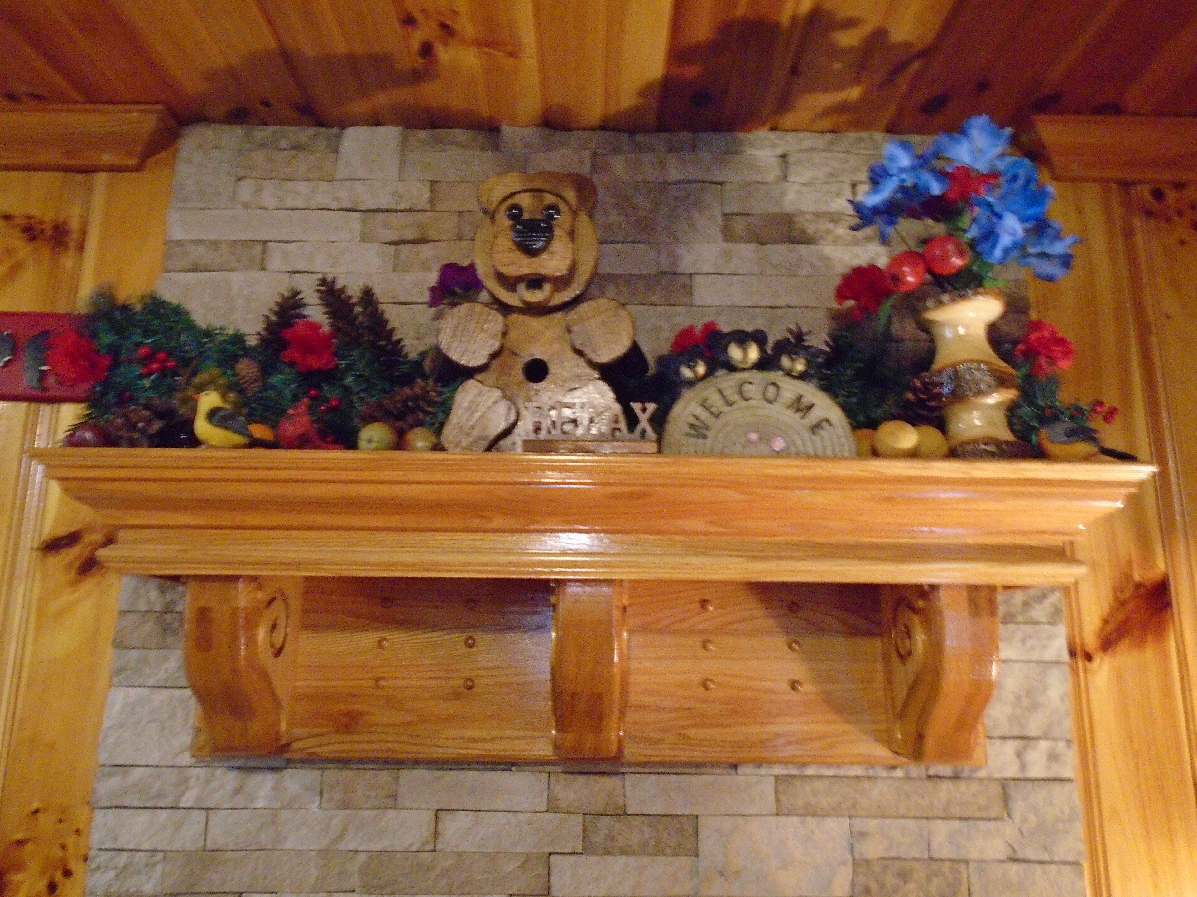 Une cheminée en bois ornée d’une décoration en forme d’ours, d’une pancarte de bienvenue et de divers éléments décoratifs de Noël.