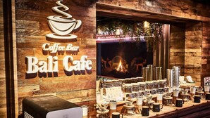 A coffee bar with a rustic wooden interior, a sign reading "Coffee Bar Bali Cafe", and a variety of coffee-related items displayed on the counter.